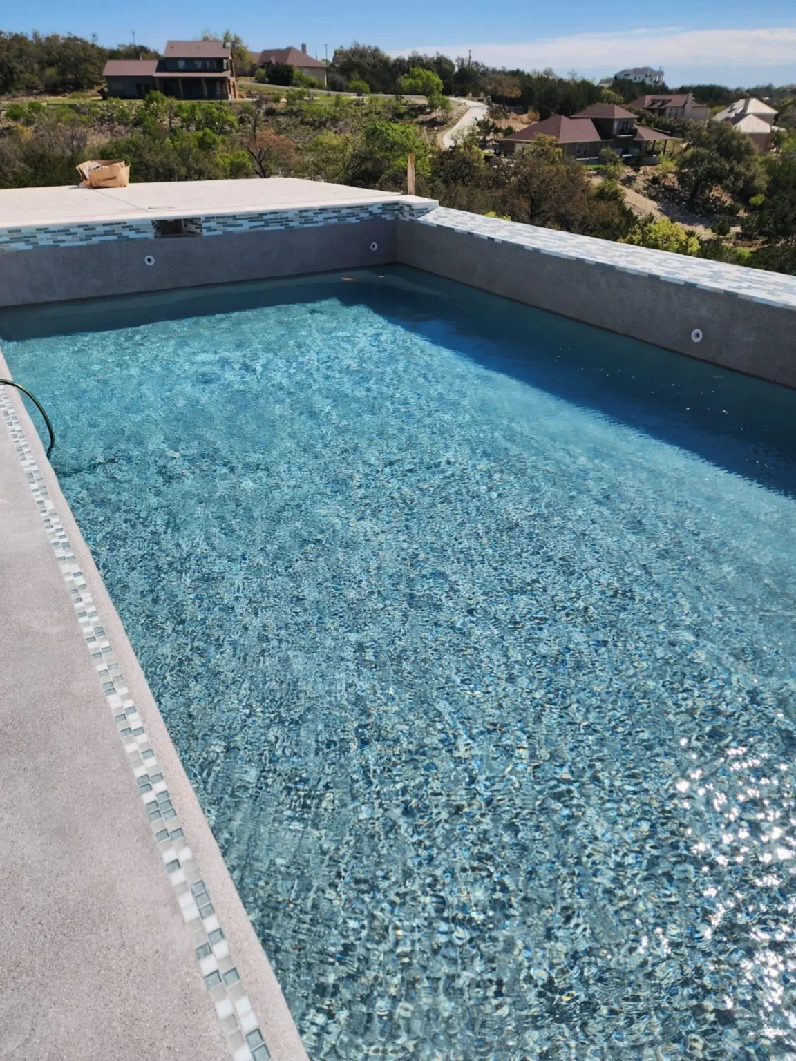 Newly constructed rectangular swimming pool with glass tile trim